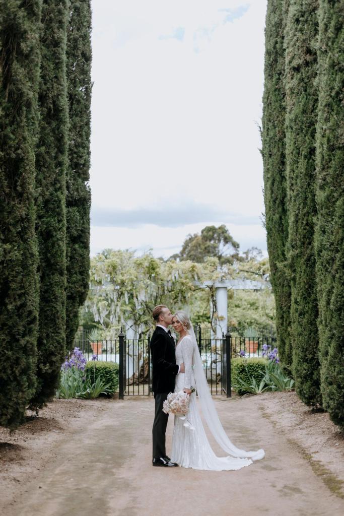 Perry - Karen Willis Homes - Laura & Ben - Bride and groom taking beautfiul couple wedding portraits, after their ceremony, while beautfiul bride is seen wearing the sophisticated and classic Perry gown from the LUXE collection. Featuring a wide open back.