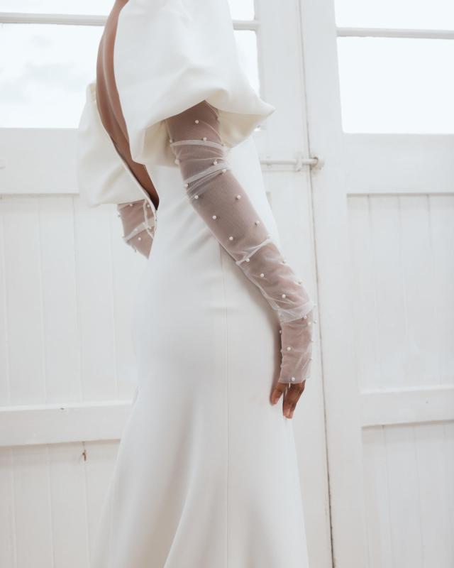 The Shelby wedding dress is a timeless versatile crepe gown featuring a centre split and bubble sleeves for a modern twist and our Erin pearl gloves. by Karen Willis Holmes 2023 Bridal Campaign.