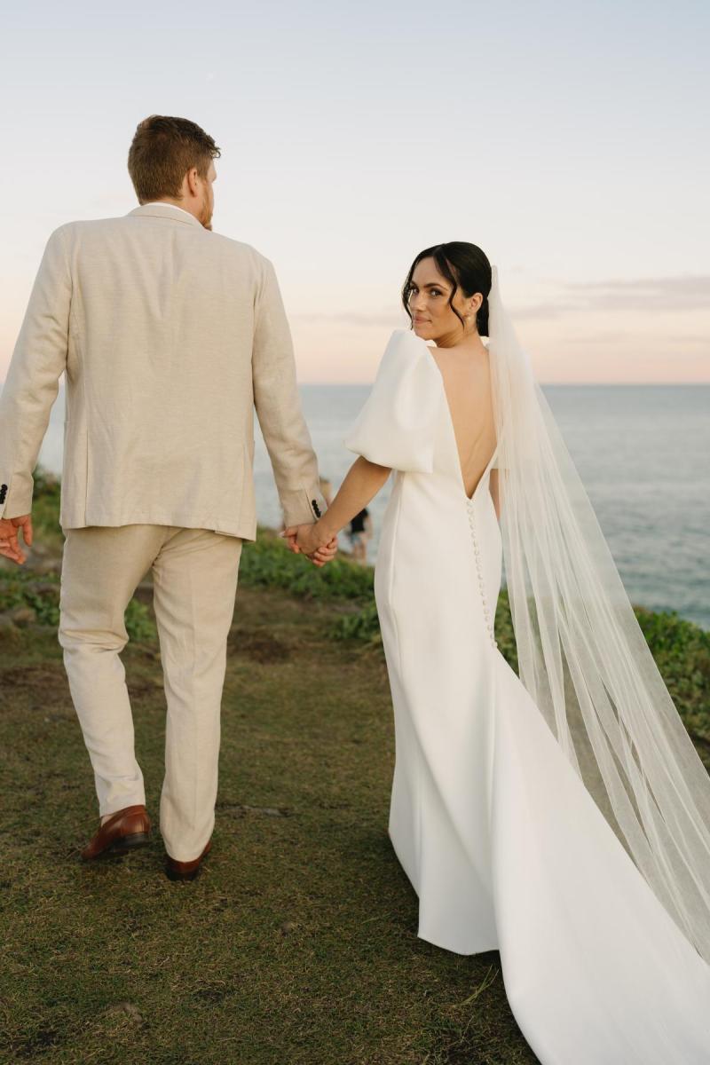 The Shelby wedding dress by Karen Willis Holmes is a sheath cut simple classic gown with a V neck, low back and statement bubble sleeves.