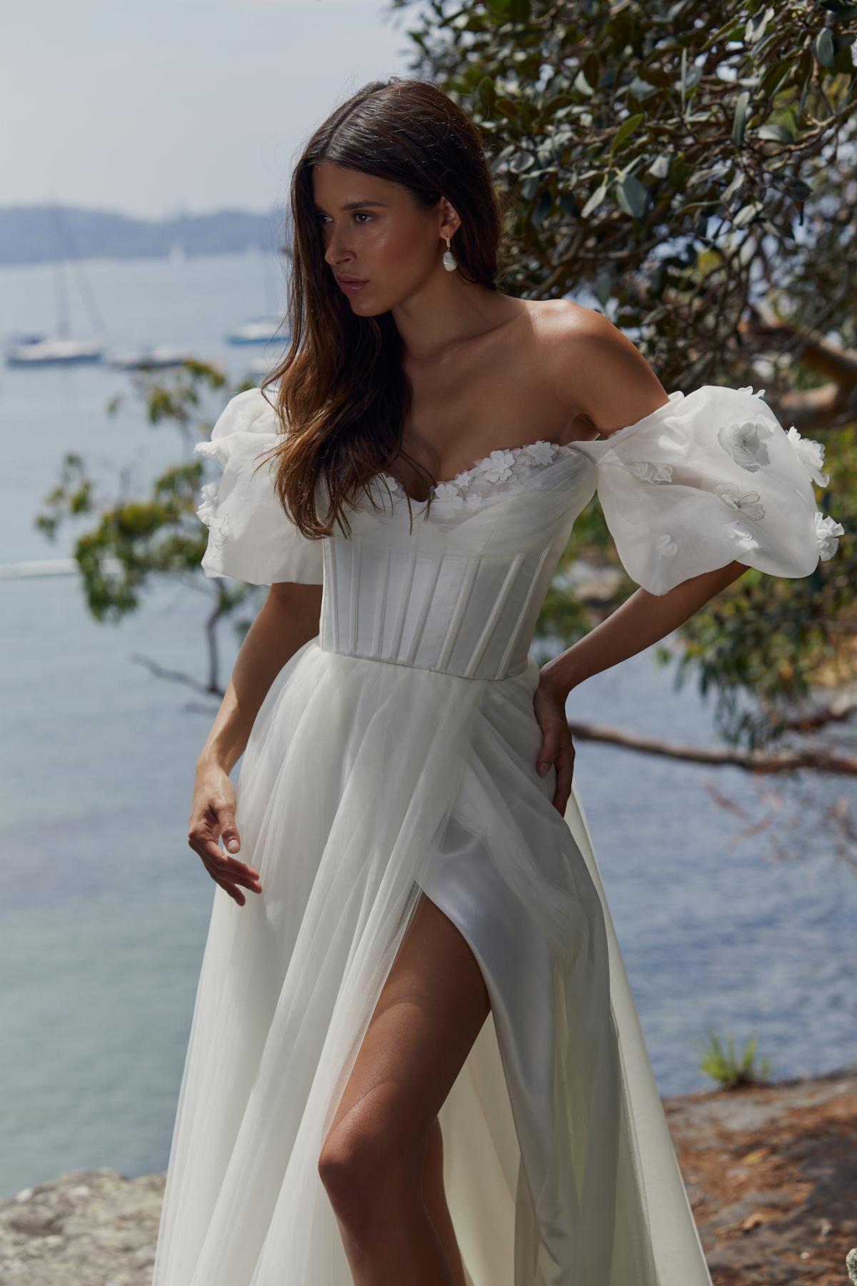 Styled with our Denisa 3D Floral Sleeve, the Rhianna & Jules gown. The Rhianna Bodice features a classic shape and modern floral embroidery. Paired with the Jules Skirt with high statement side-split in a soft tulle fabric.
