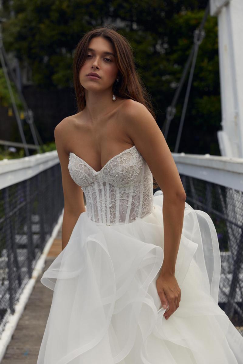 Eden & Selena is a wedding dress for the romantic bride. The Eden bodice features hand draped corded lace and pearl detailing over a sheer corset Paired with the Selena skirt that features layers upon layers of circle cut organza.