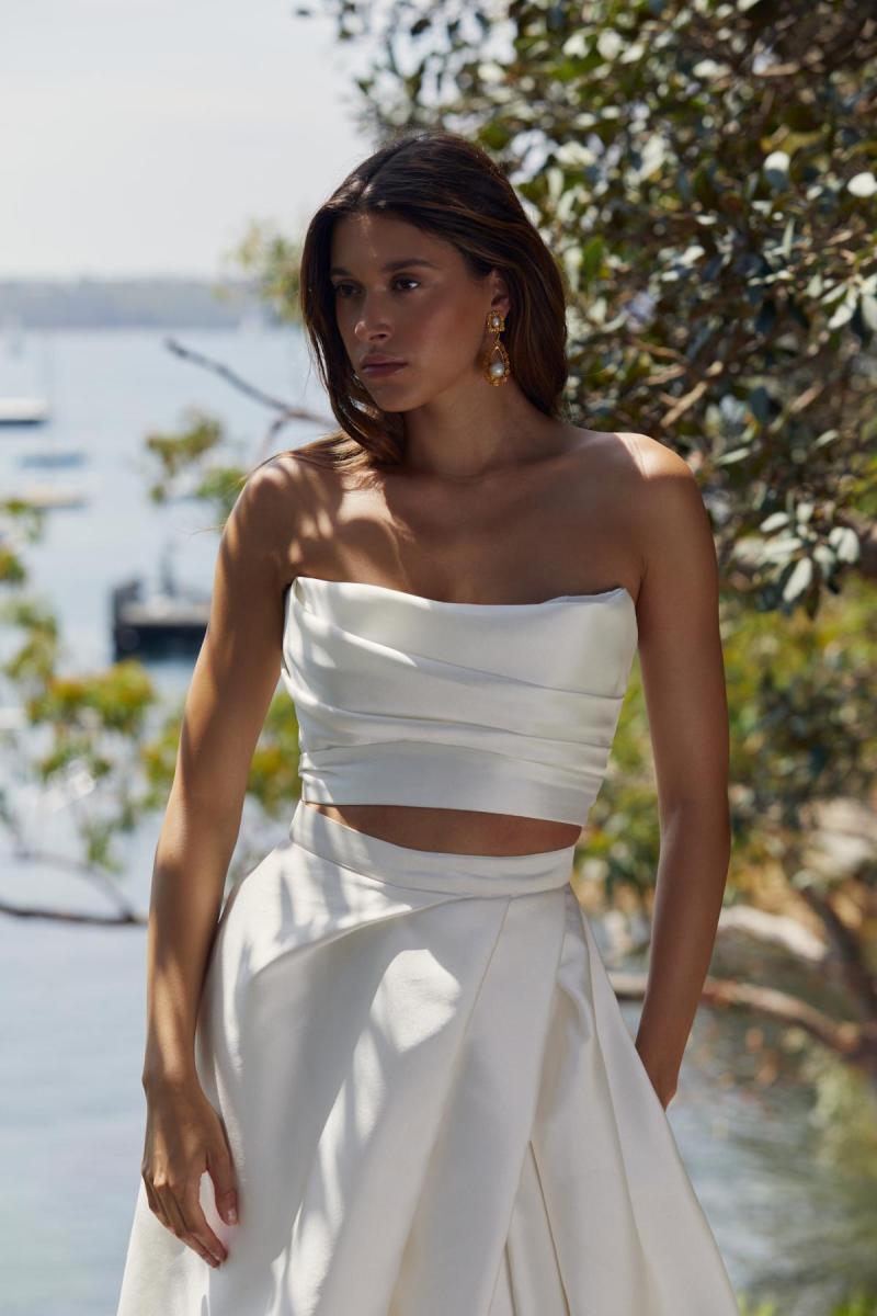 Lou Lou bralette and Gianna skirt is a sexy modern wedding gown. Lou Lou bralette is a strapless draped crop bodice and is paired with the Gianna skirt which also features a modern drape style, pockets and a statement split.