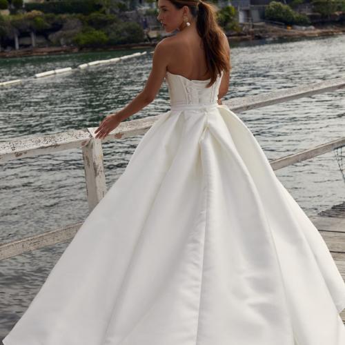 Styled with our Lizzie Train, the Evie & Neve Mini gown is classic with a modern flair. The Evie Bodice features a stunning scoop neckline and detachable drape to complement your décolletage with statement pipe boning lines for that touch of drama. The Neve Mini Skirt is the perfect match for brides who love a modern twist.