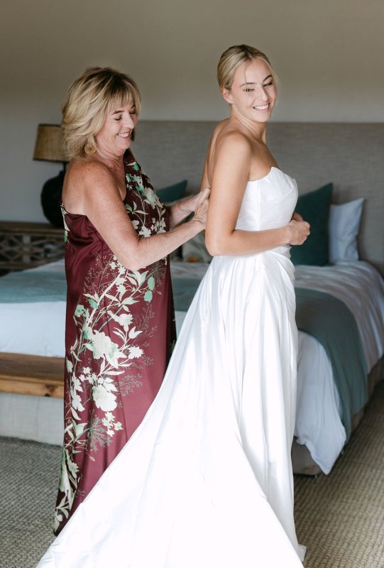 Mom of the bride helping Rebecca getting dressed In our beautiful Emma gown