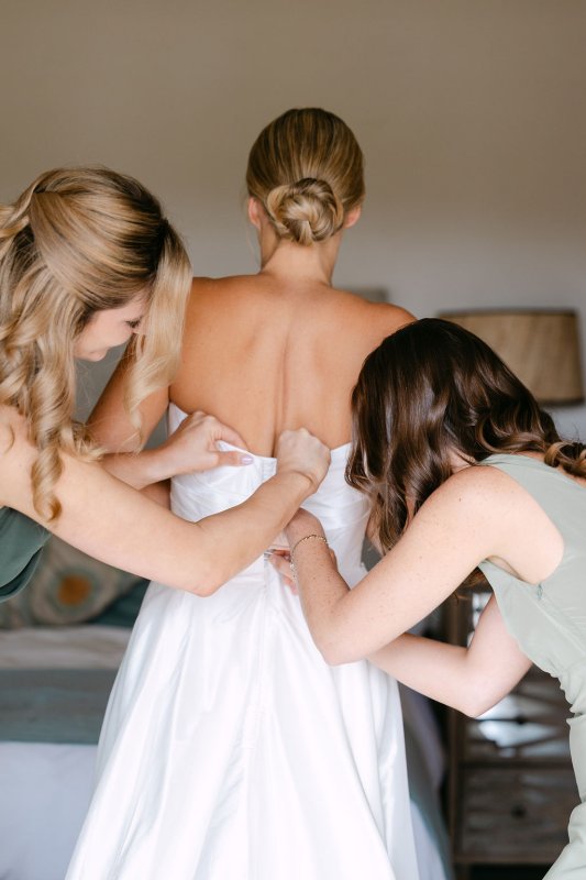 Bride's maids helping Rebecca getting dressed In our beautiful Emma gown